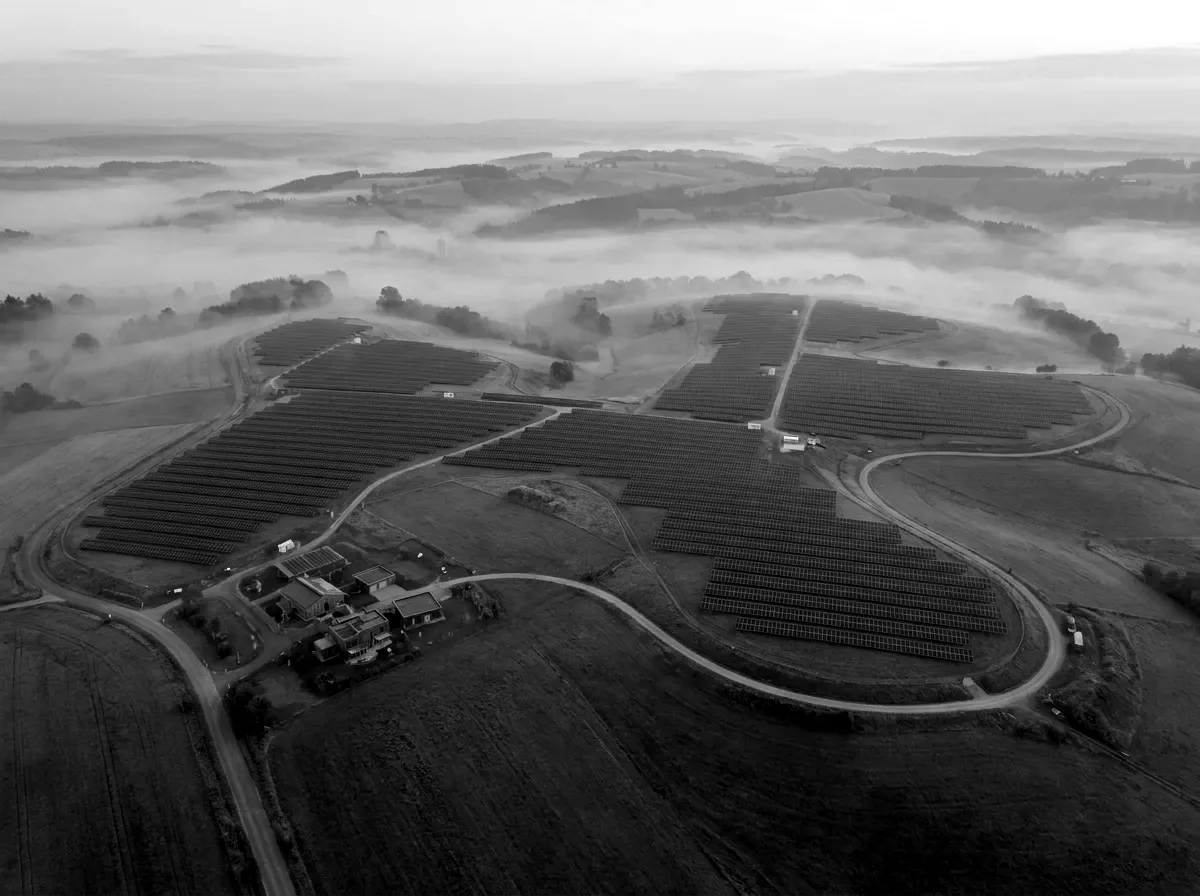Solar energy fields across a misty landscape